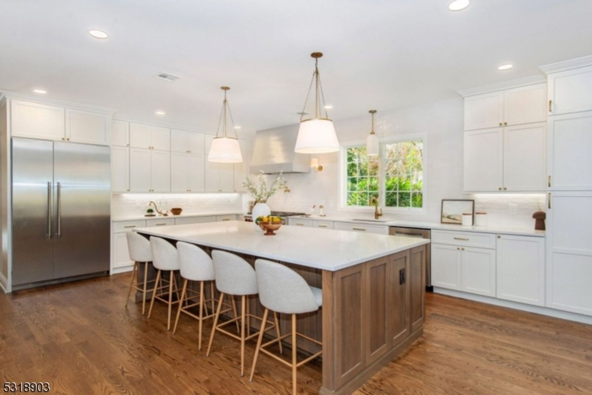 Gourmet kitchen showcases a large center island with seating, modern light fixtures, and custom cabinetry for a sleek and functional design.