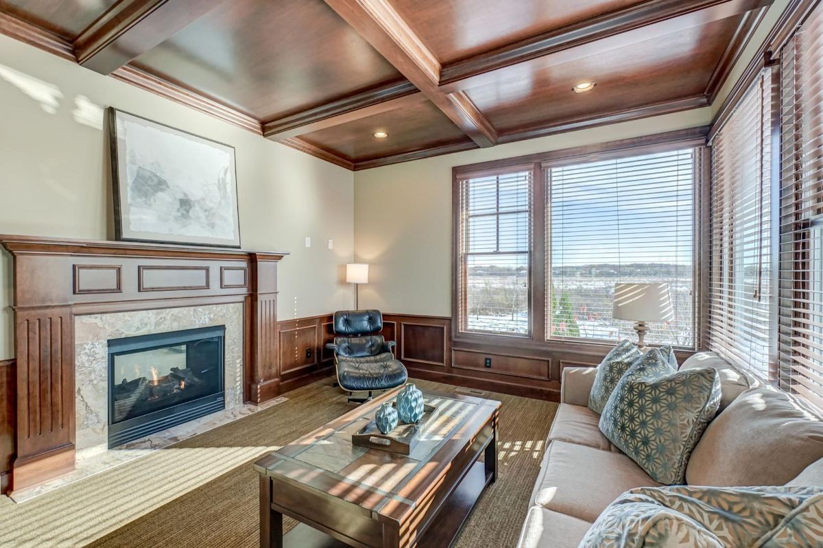 Elegant study featuring coffered ceilings and a warm fireplace.