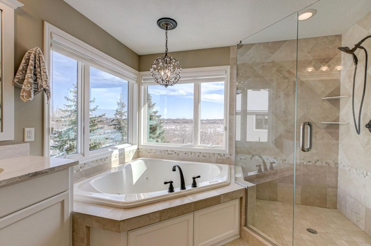 Elegant bathroom featuring a spa-like tub and glass-enclosed shower with serene views.