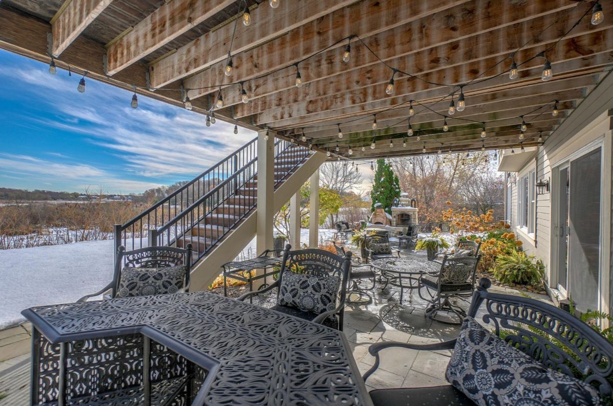 Cozy patio adorned with string lights offers a charming space for outdoor gatherings amidst a snowy backdrop.