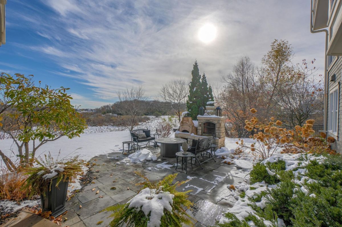 A scenic patio featuring a built-in fireplace and cozy seating creates an inviting outdoor retreat with stunning views of a snowy landscape.