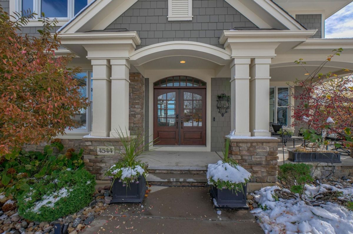 The stately front entrance boasts a double-door entry framed by classic columns and stone accents, creating a welcoming and elegant facade.