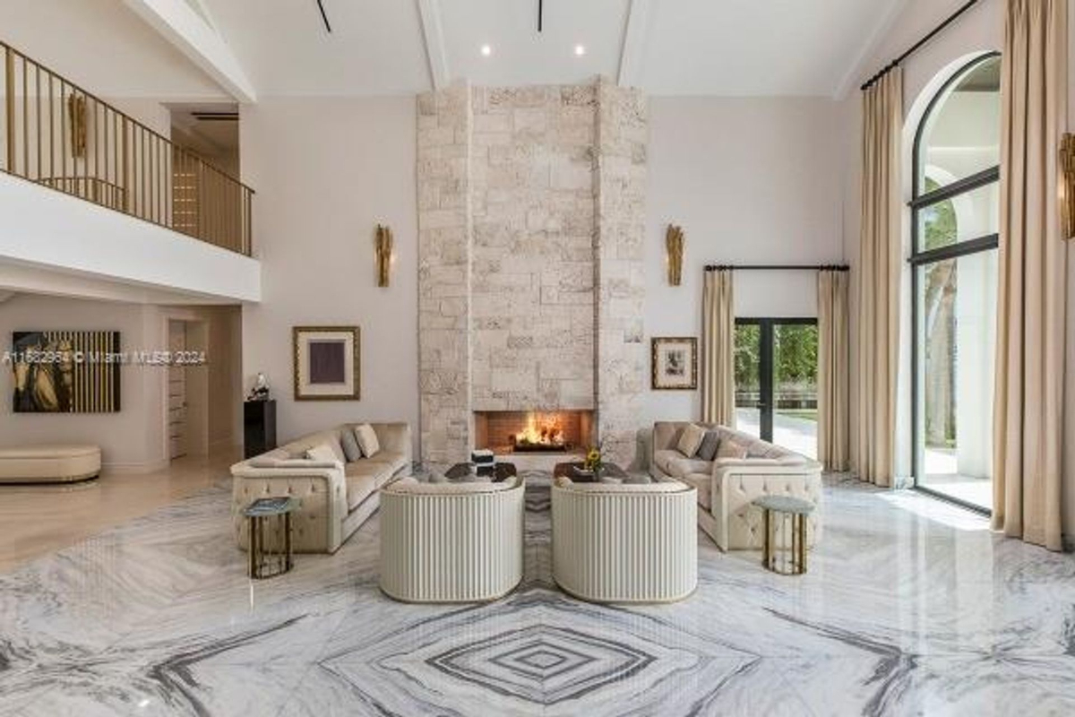 A grand living room showcases a soaring stone fireplace, custom marble flooring, and elegant seating arrangements.