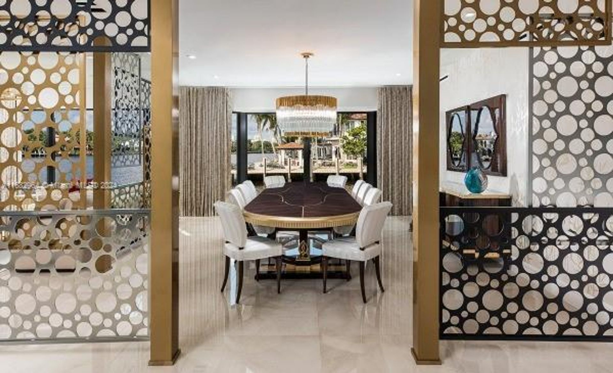 Dining area features a modern chandelier, geometric accents, and waterfront views.