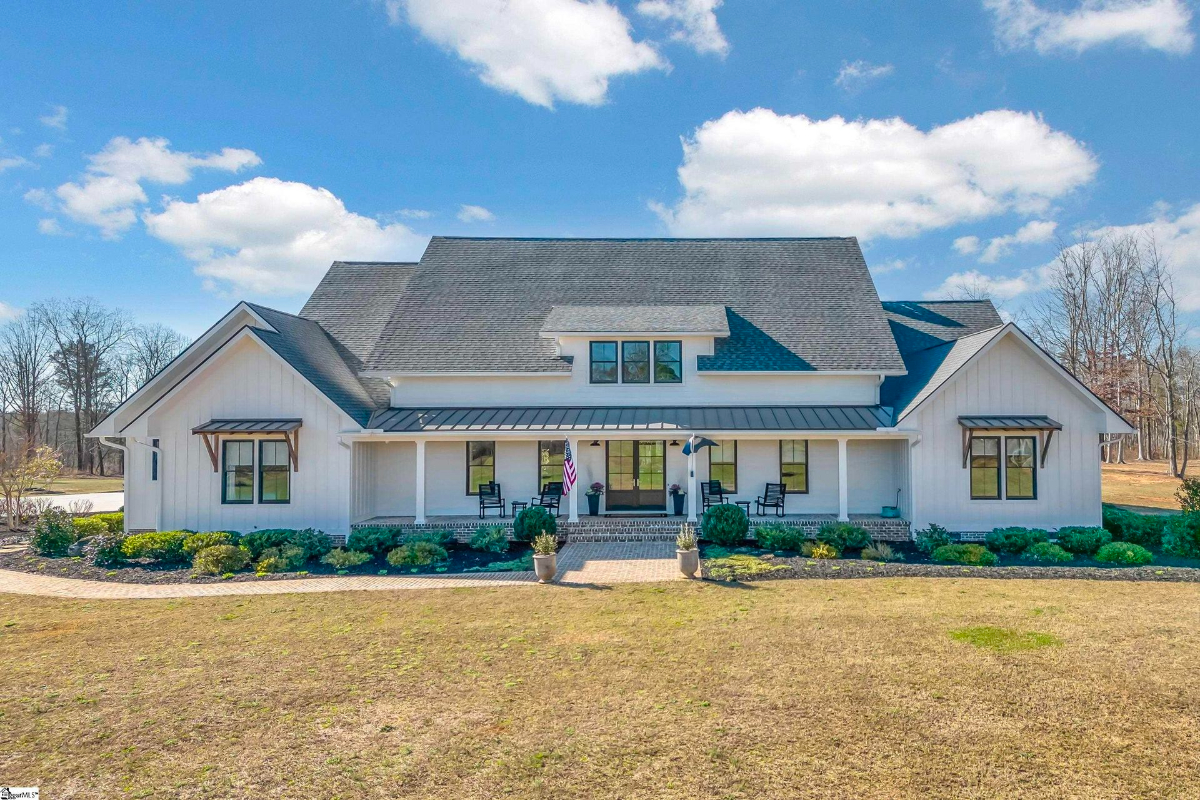 Bright and inviting modern farmhouse with a spacious front porch and charming landscaping.