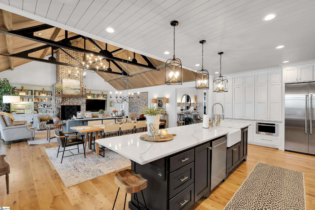 Bright and airy kitchen featuring a large island with quartz countertops, modern lantern-style pendant lighting, and custom cabinetry.