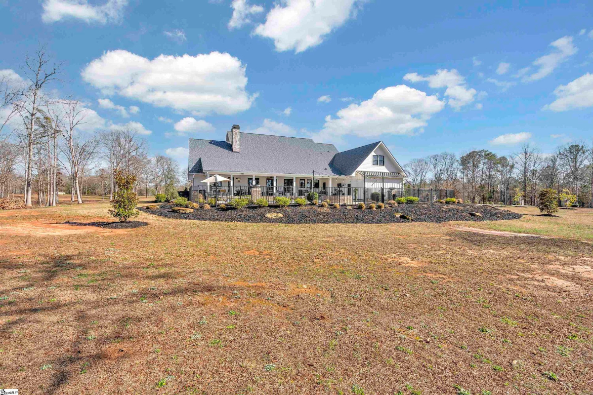 Expansive backyard featuring a covered patio and meticulously landscaped garden beds, perfect for outdoor living.