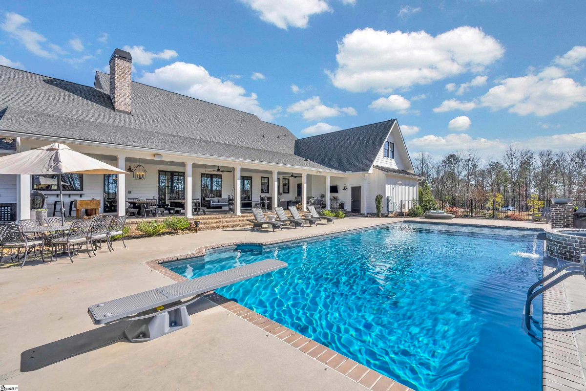 Outdoor oasis featuring a sparkling pool, diving board, and a spacious covered patio ideal for relaxation and entertainment.