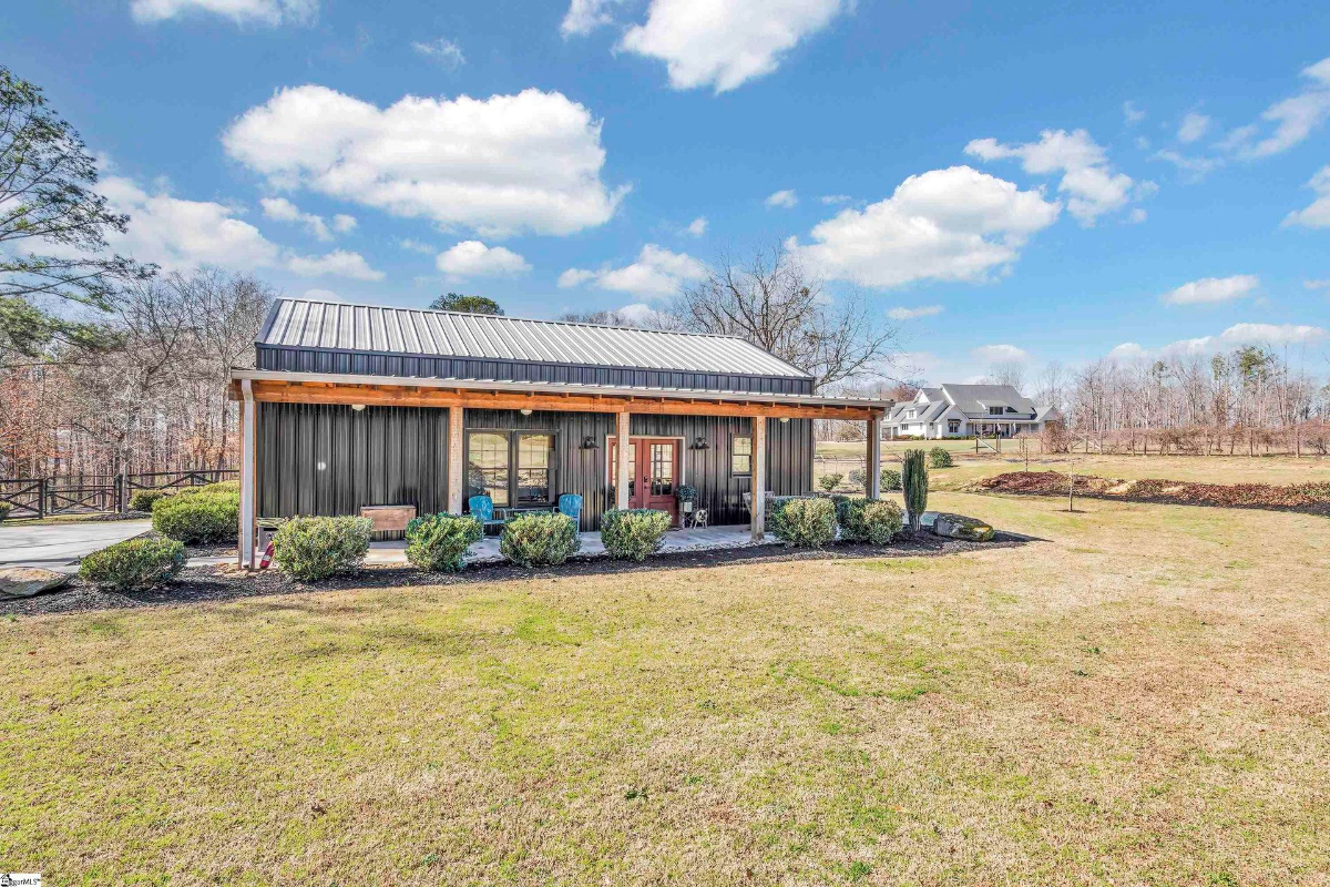 Modern barn-style structure with a covered porch, rustic wood accents, and scenic surroundings.