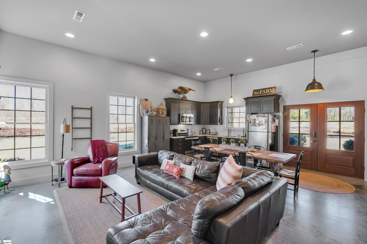 Open-concept living area with rustic charm, featuring a leather sectional, farmhouse-style kitchen, and ample natural light.