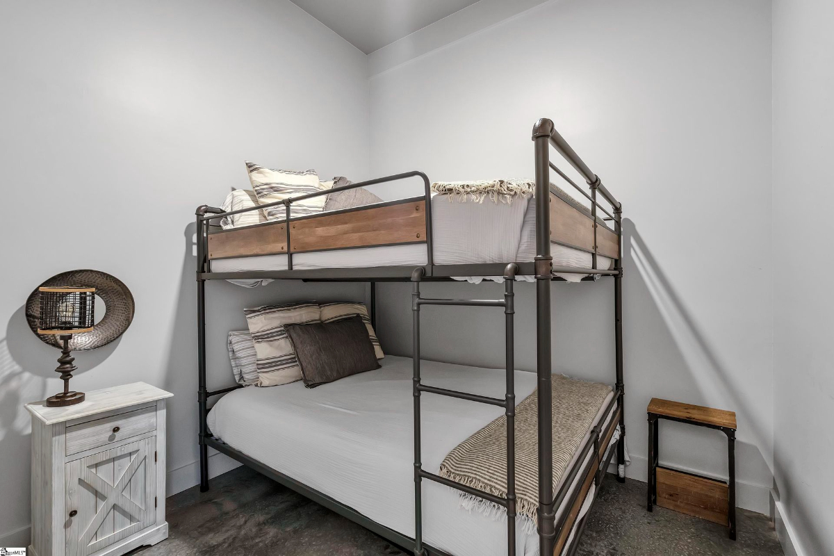 Cozy bunk room featuring industrial-style metal framing and a rustic nightstand.