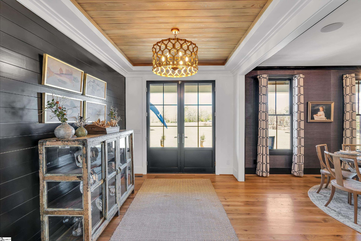 Sophisticated entryway featuring shiplap walls, a wood-paneled ceiling, and stylish accents with natural light streaming through glass double doors.