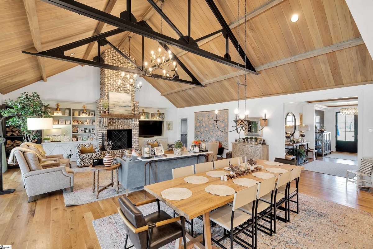  Rustic charm meets modern elegance in this open living and dining space with vaulted ceilings, a brick fireplace, and curated built-ins.