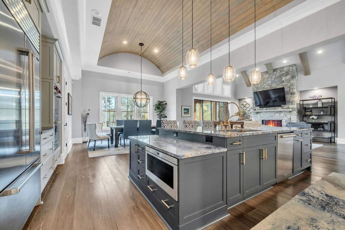 Open-concept kitchen and living area boasts vaulted wood ceilings, elegant pendant lighting, and seamless flow into the dining and relaxation spaces.