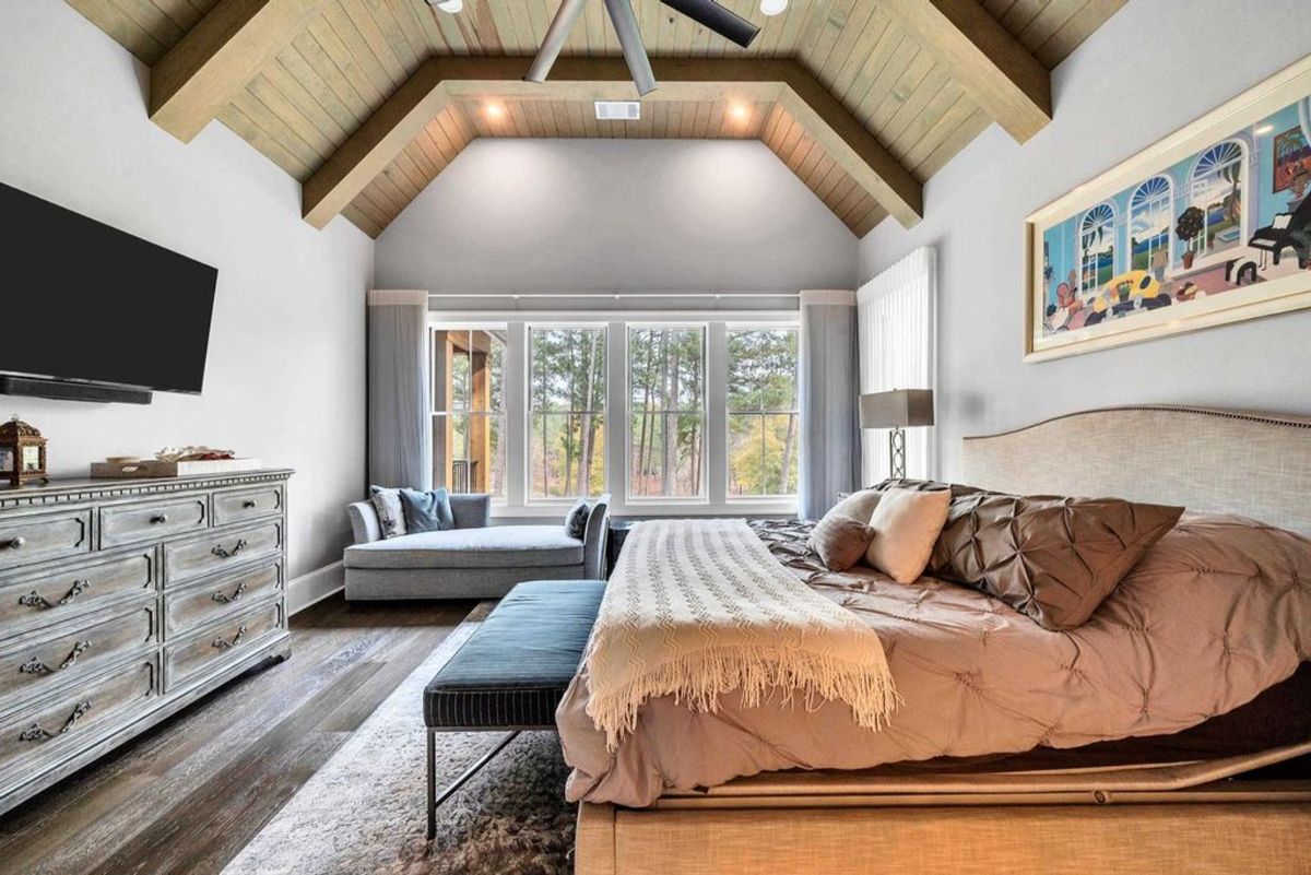 Vaulted ceiling and large windows create a serene ambiance in this inviting bedroom retreat.