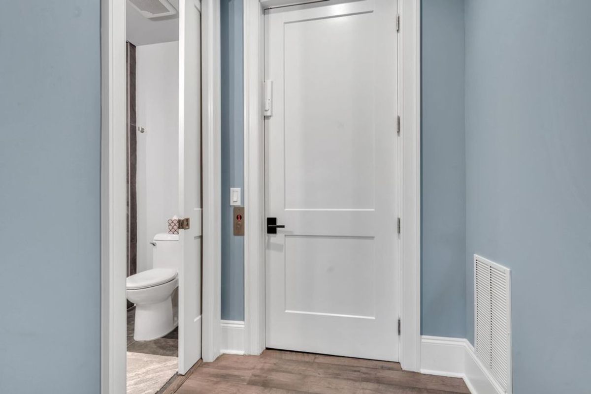 A hallway corner with a clean and modern design showcases white doors and a calming blue wall, leading into a connected bathroom.