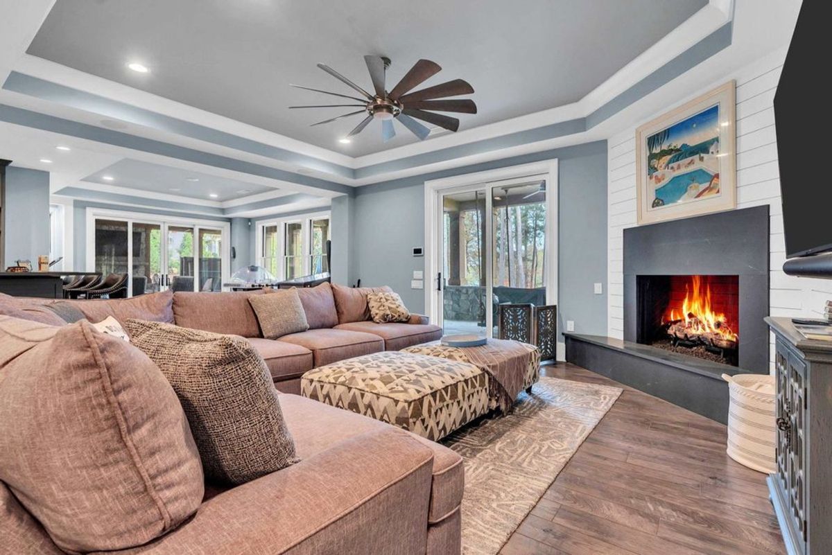 An inviting family room showcases a warm fireplace, ample seating, and access to outdoor living spaces.