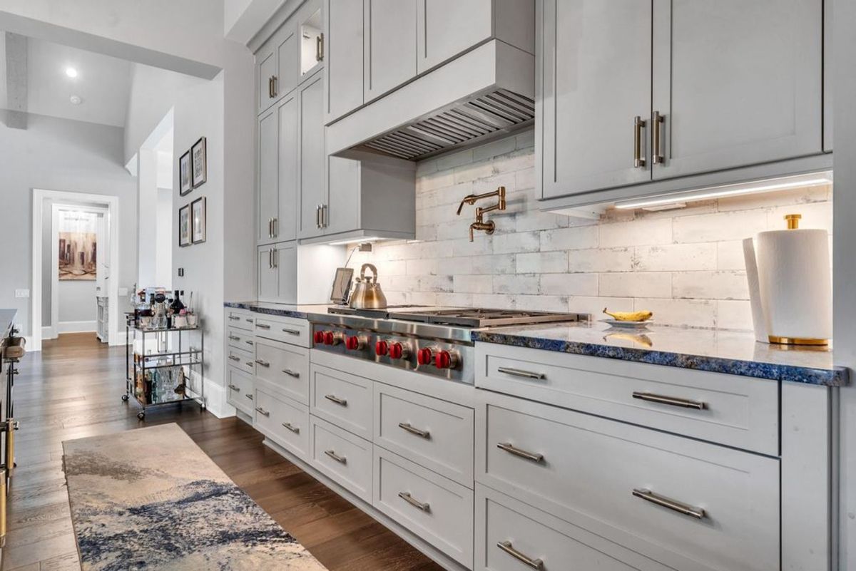 A gourmet kitchen features high-end appliances, a pot filler over the stove, and custom cabinetry with a sleek backsplash for added sophistication.