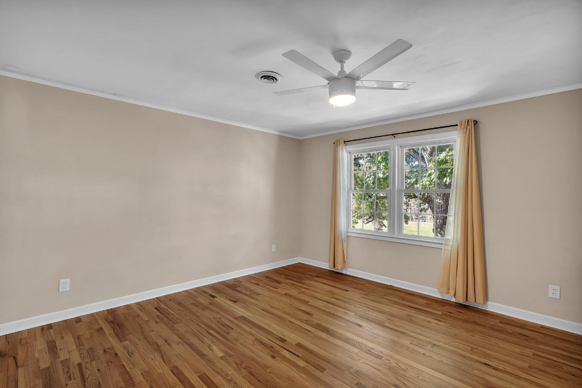 Bedroom offers ample natural light through large windows and features polished hardwood flooring.