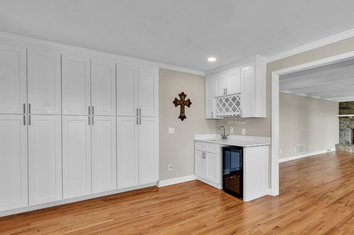 This well-appointed wet bar area features ample cabinetry, a wine rack, and a mini fridge, seamlessly blending functionality and style.