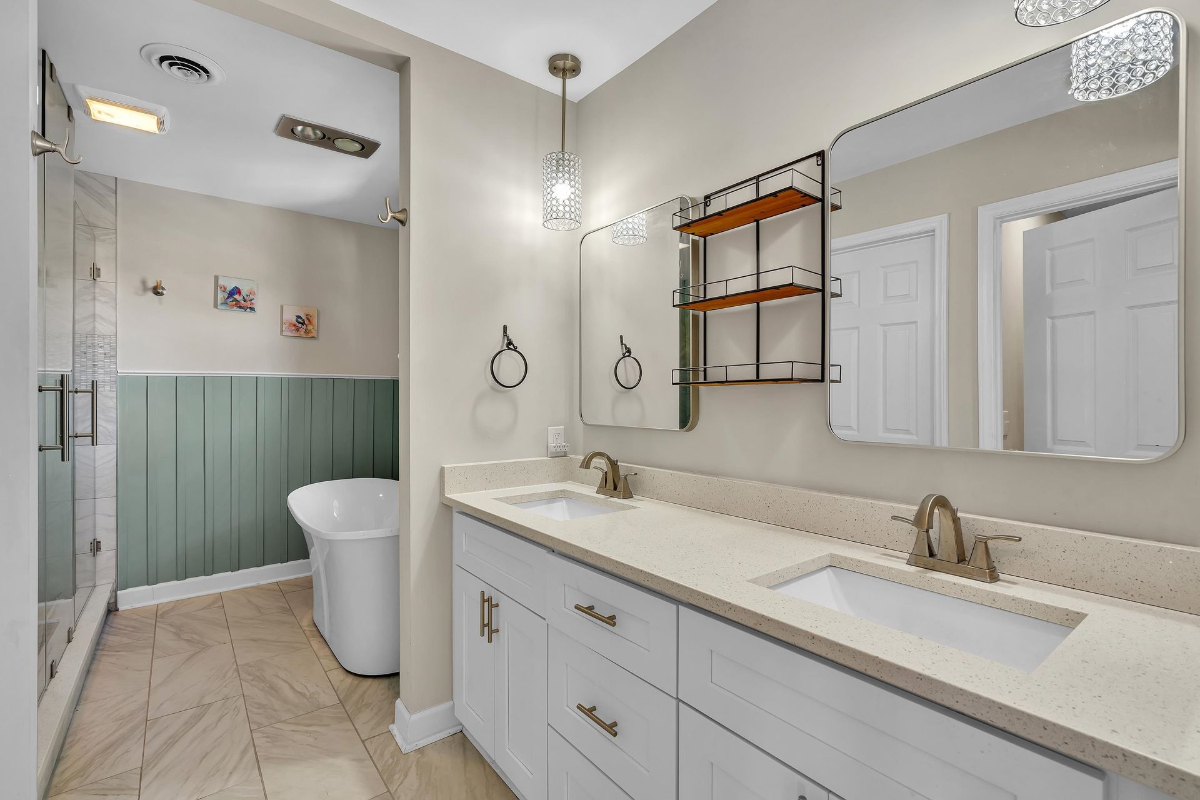 Bathroom showcases dual vanities, stylish pendant lighting, a modern soaking tub, and a spacious glass-enclosed shower.