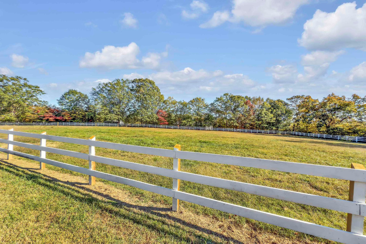 Rolling green pasture is bordered by classic white fencing, creating a picturesque and tranquil setting.