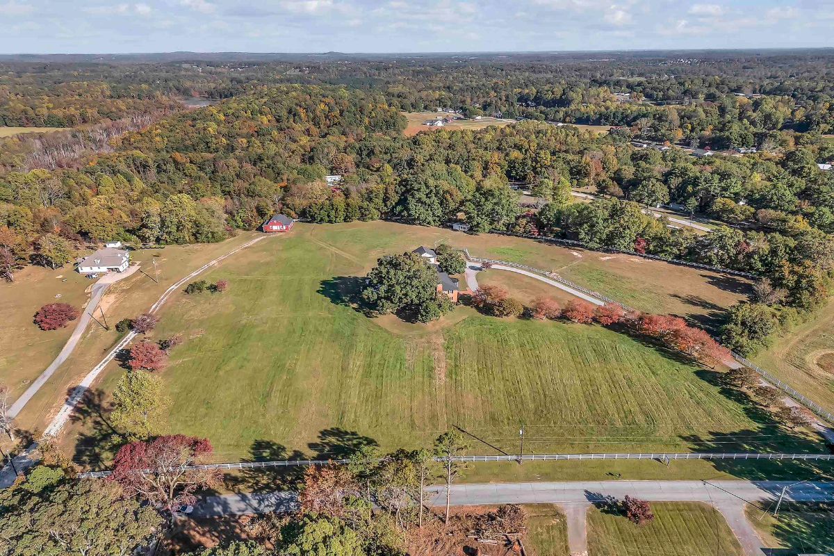 Aerial views capture expansive acreage surrounded by lush greenery, winding driveways, and charming outbuildings.