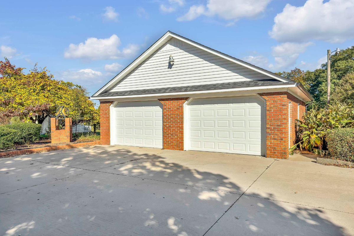 Car garage with a classic brick exterior is complemented by a well-maintained driveway.