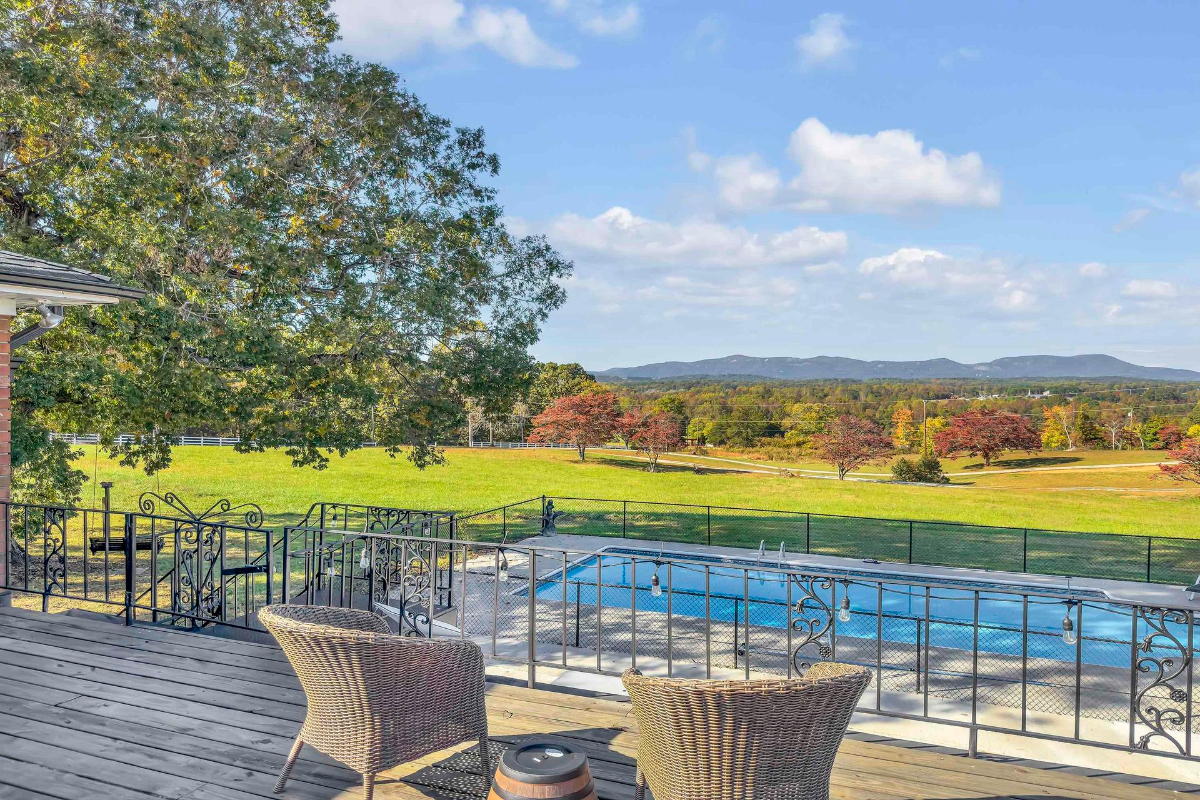 Elegant seating on the rooftop deck overlooks a serene pool and lush rolling hills, offering a perfect retreat for quiet moments or scenic enjoyment.