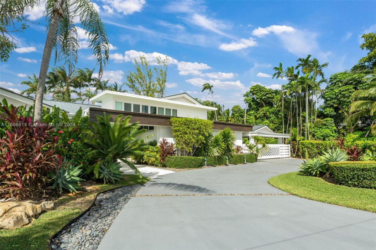 Tropical retreat with vibrant landscaping and a modern white facade.