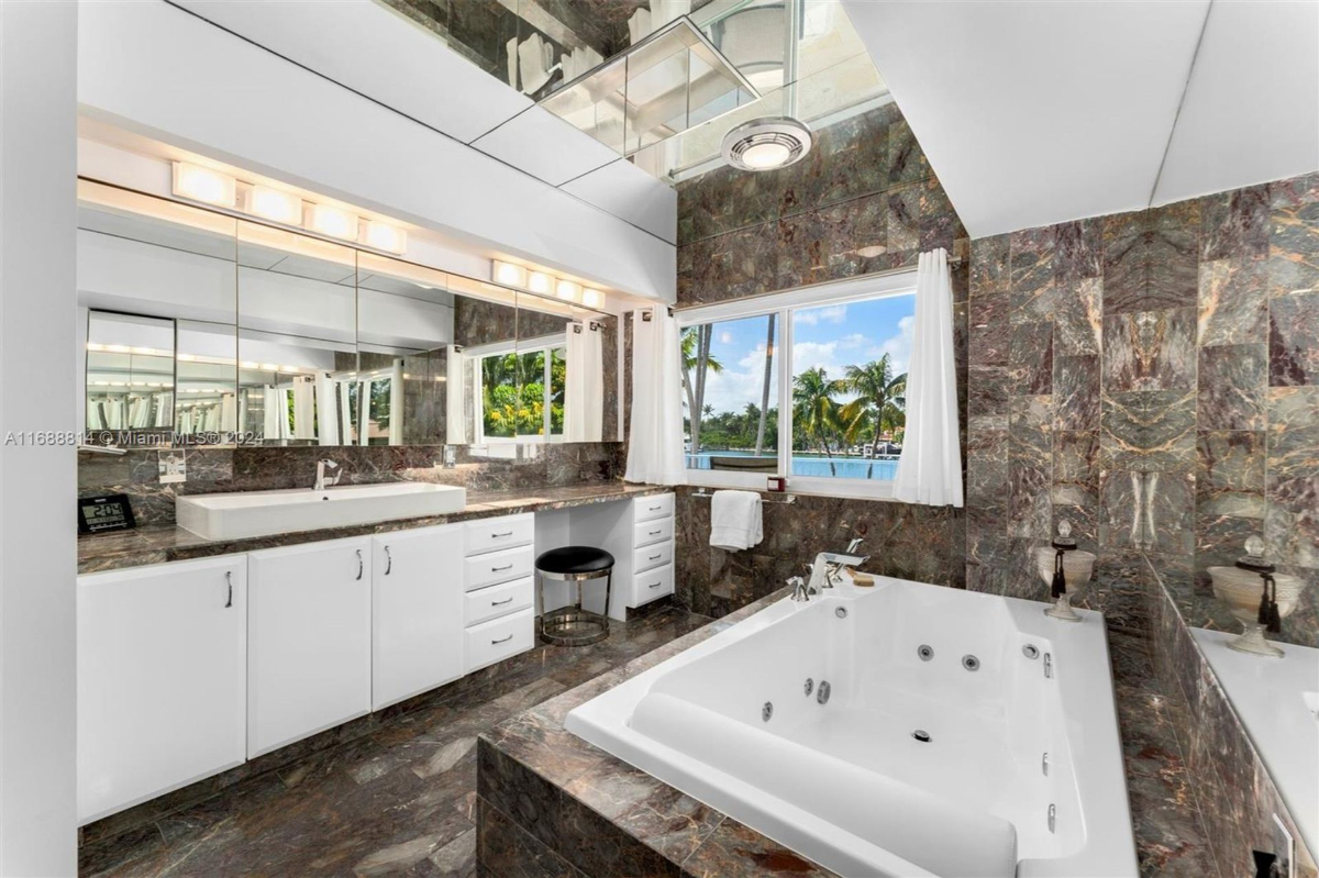 Bathroom with marble walls, a large soaking tub, and scenic water views.