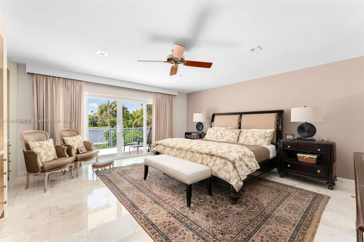 Elegant master bedroom with sliding glass doors opening to a balcony overlooking the waterfront.