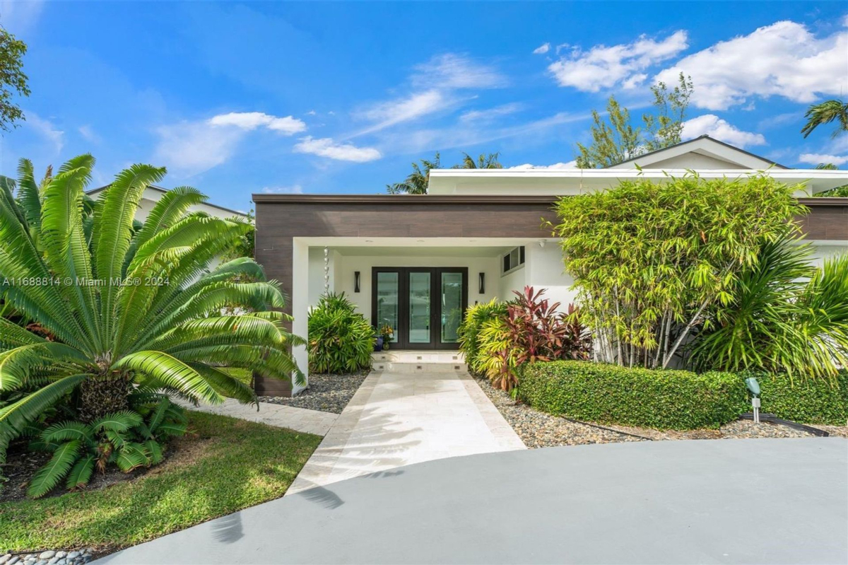 Modern front entrance with lush landscaping and a sleek overhang design.