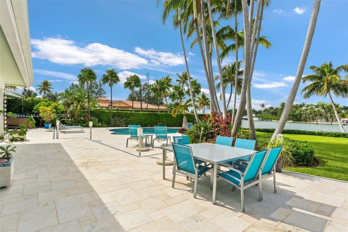 Outdoor dining and lounging area with poolside views and lush tropical landscaping.