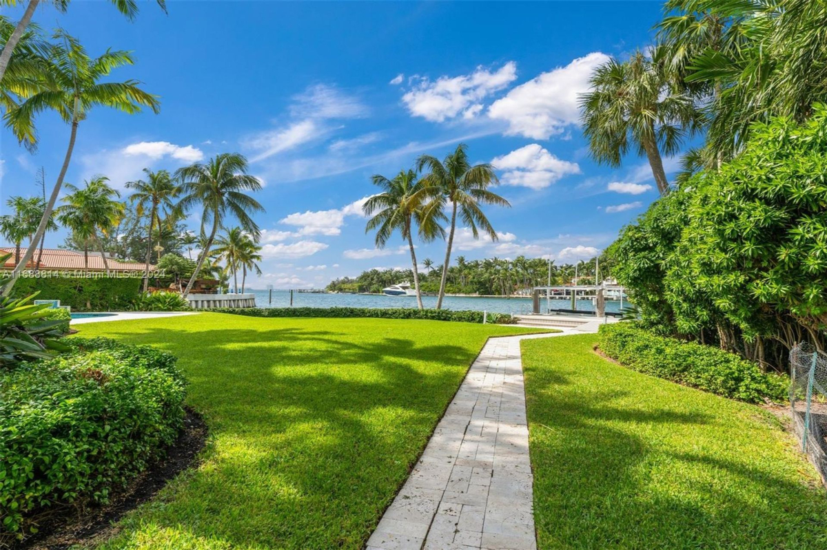 Pathway leading to a waterfront dock, surrounded by tropical landscaping and lush greenery.