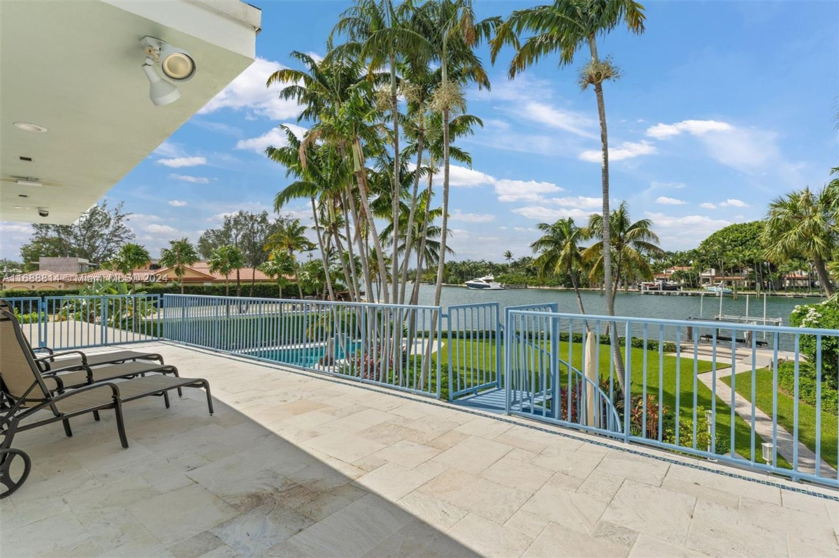 Balcony overlooking lush landscaping, a pool, and waterfront views.