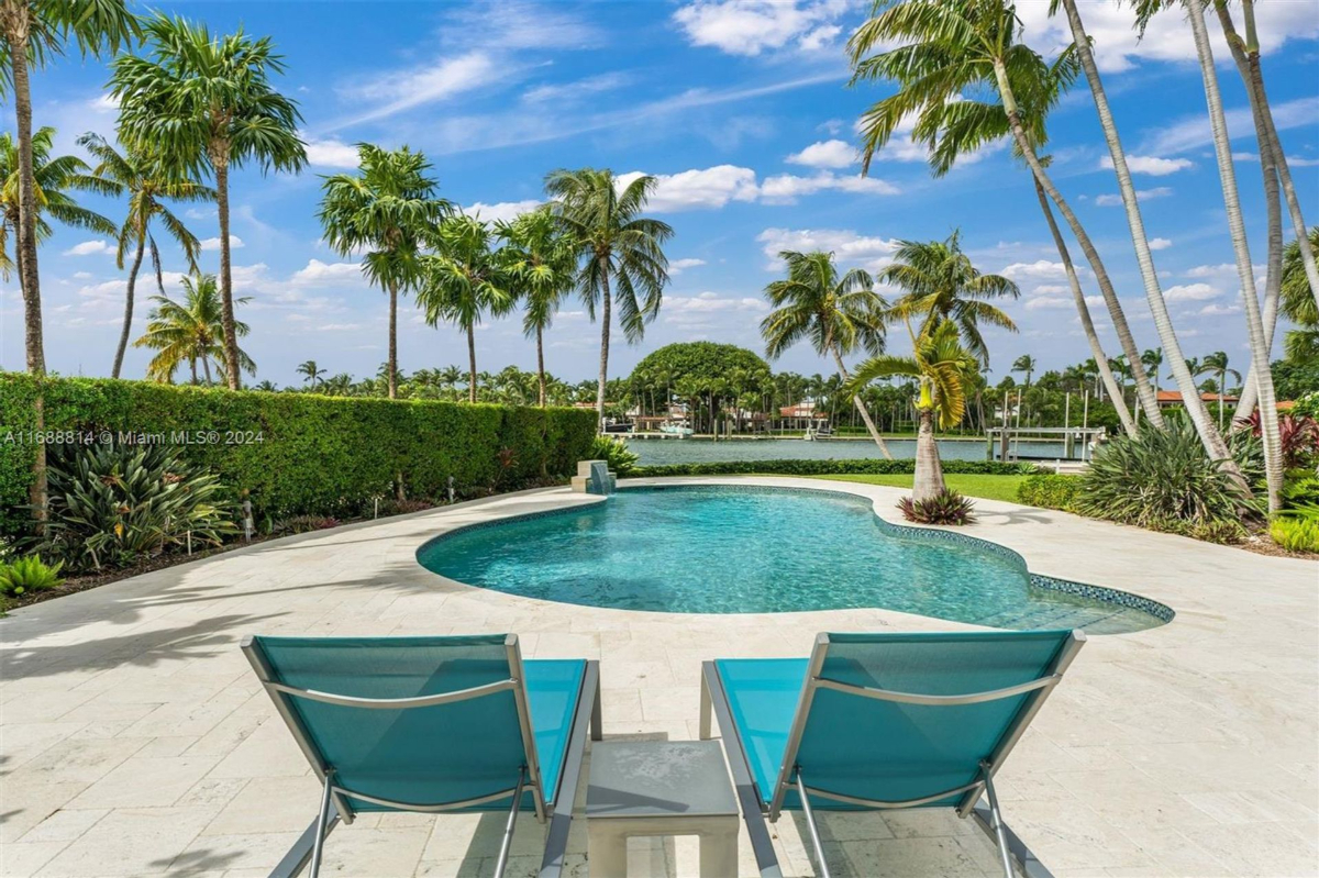 Poolside seating with scenic views of tropical palm trees, lush greenery, and the tranquil waterfront.