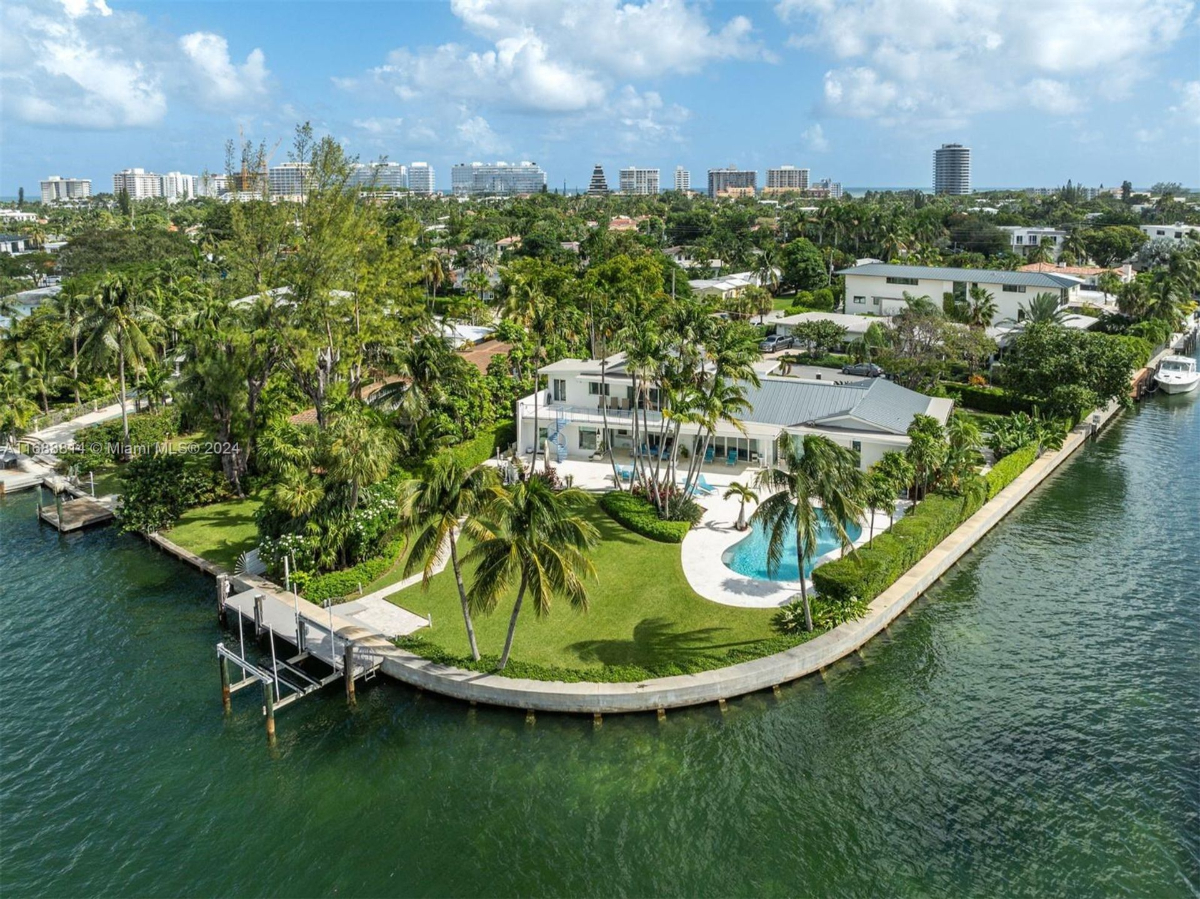 Waterfront property featuring lush landscaping, a private dock, and a sparkling pool.