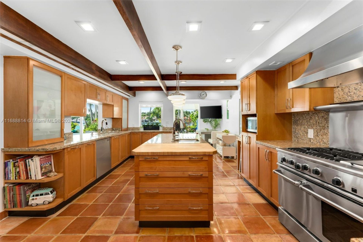 Modern kitchen with natural wood cabinetry, a central island, and stainless steel appliances.