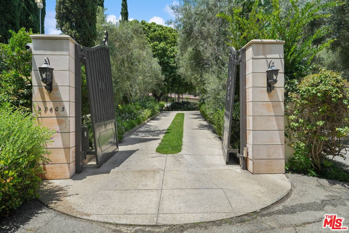 Grand gated entryway leading to a serene tree-lined driveway.