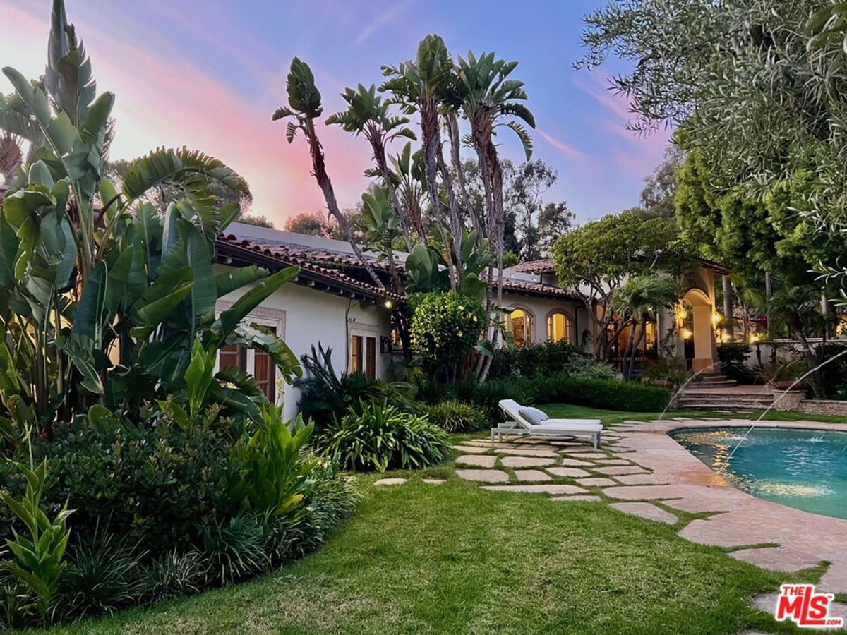 Lush garden setting with a sparkling pool and Mediterranean-style architecture.