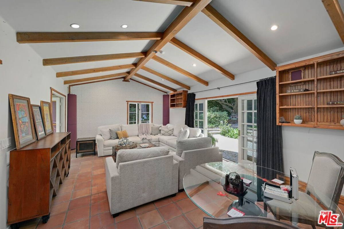 Cozy family room with vaulted wood beams, terracotta flooring, and garden access.