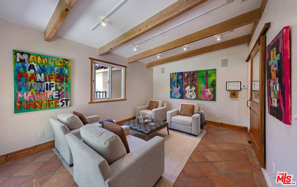 Vibrant art-filled sitting area with exposed beams and terracotta floors.