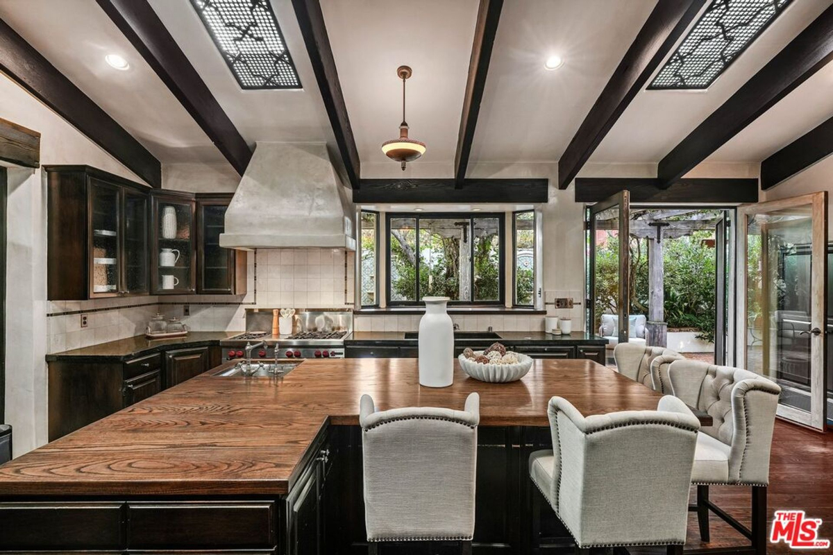 Gourmet kitchen with a large wooden island, custom cabinetry, and garden views.