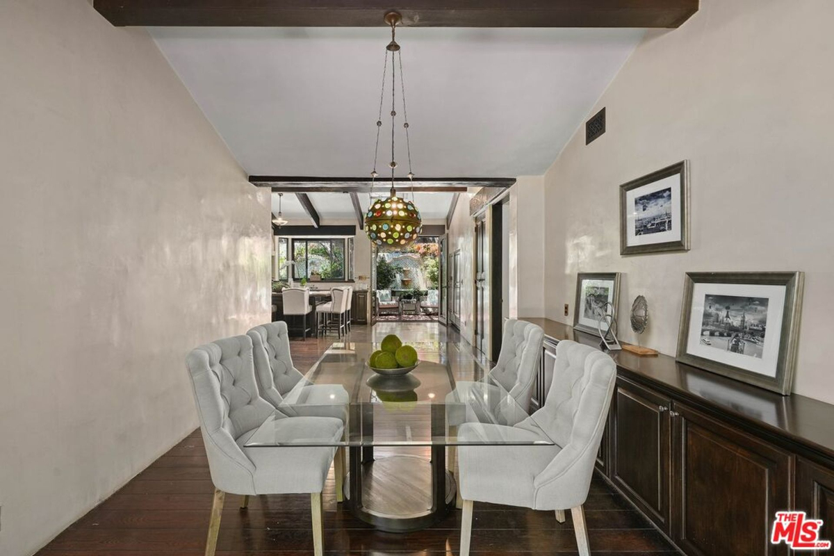 Elegant dining area with a glass table, tufted chairs, and a unique pendant light.