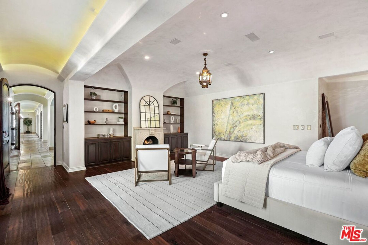 Spacious bedroom suite featuring a cozy seating area, built-in shelves, and a decorative fireplace.