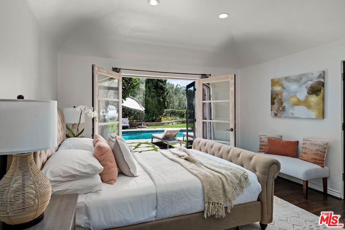 Bright bedroom with French doors opening to a poolside retreat.