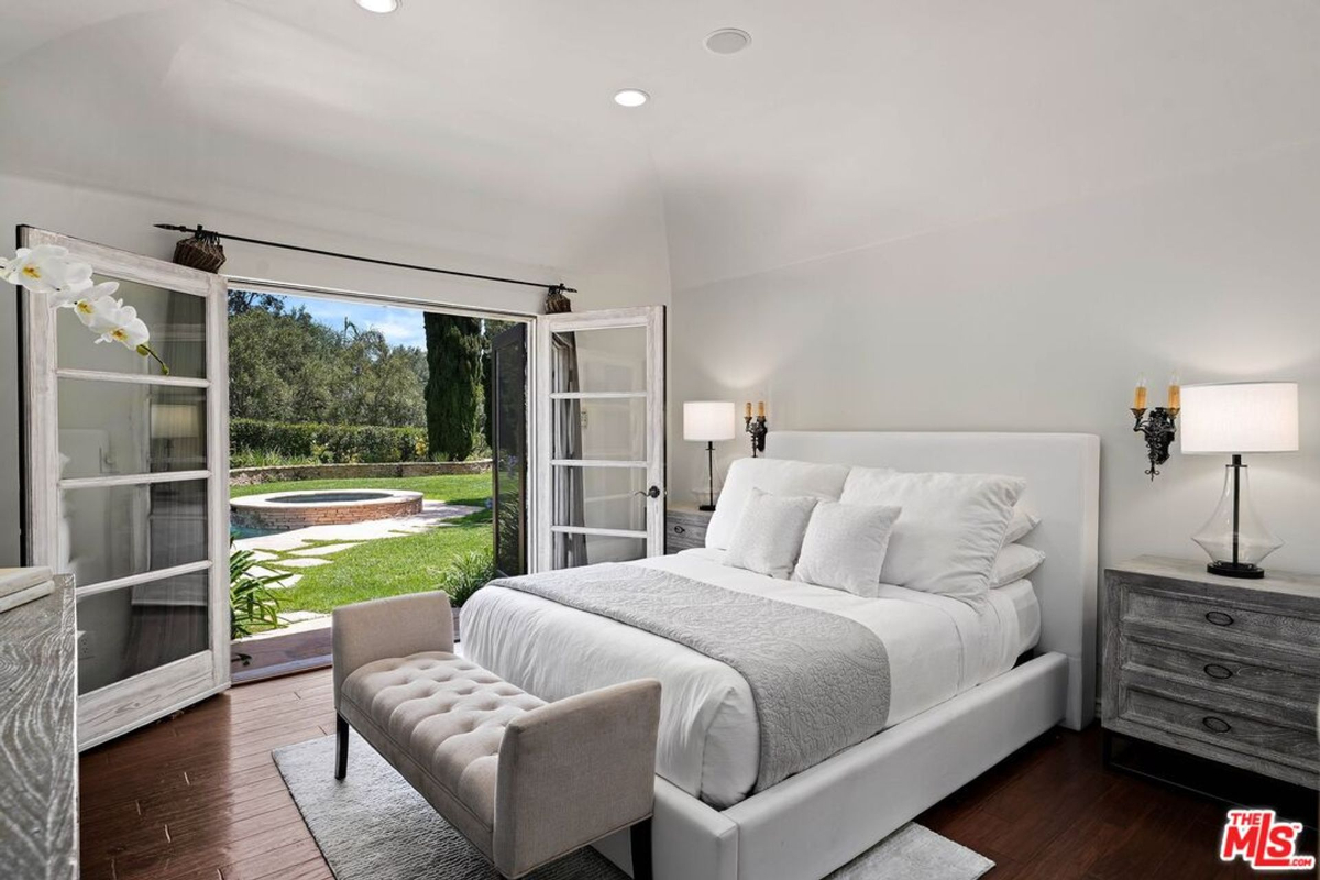 Serene bedroom with garden access and views of a private spa.