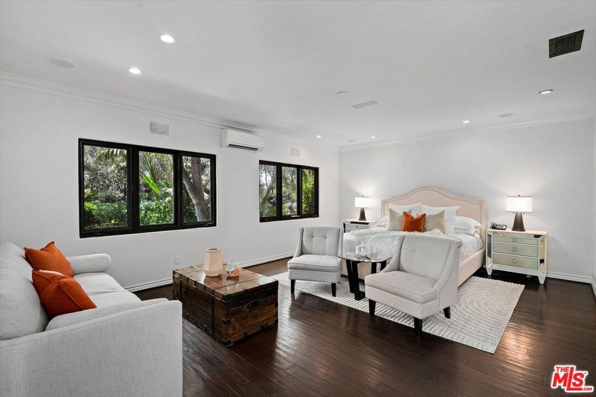 Expansive bedroom suite with modern furnishings and large windows overlooking greenery.