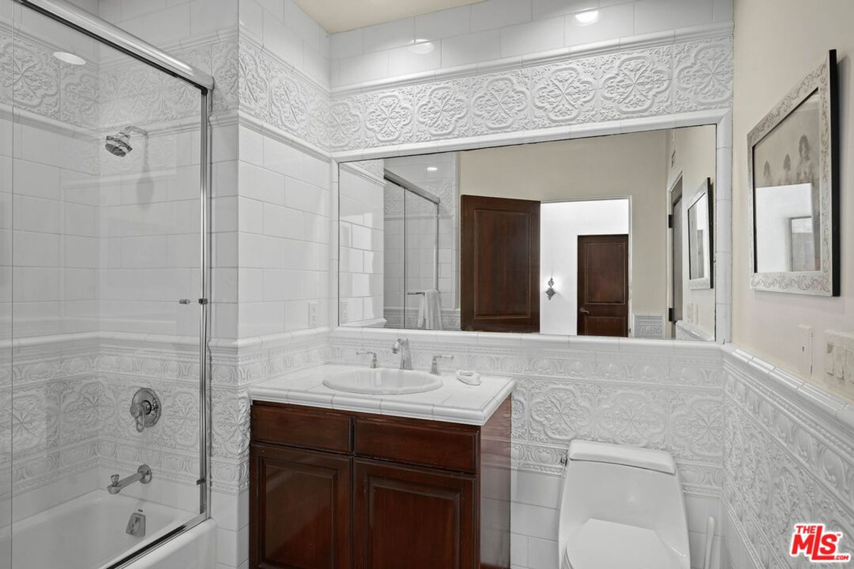 Traditional bathroom featuring intricate white tilework and a glass-enclosed shower.